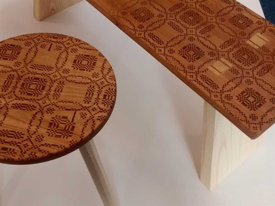 Aerial view of highly patterned round wooden stool next to a long rectangular bench also in wood. Both have geometric etched patterns and detailing of