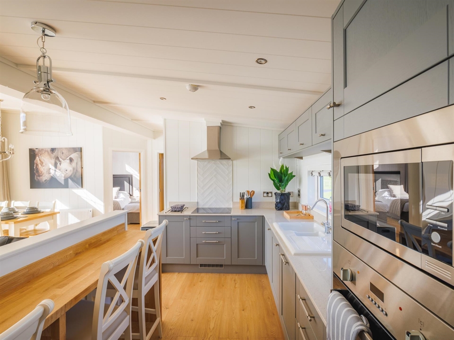 Kitchen with oven and built in microwave, hob, sink and breakfast bar.