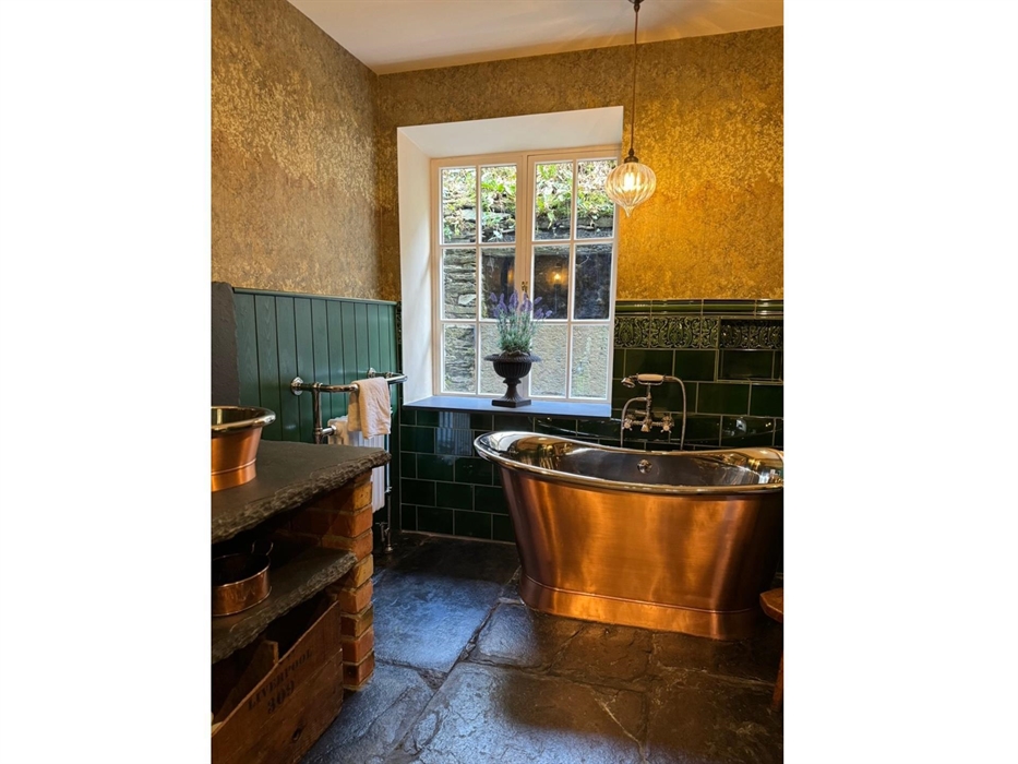 Downstairs bathroom with copper bath and copper basin in Coedfa Bach.  On an original slate floor.