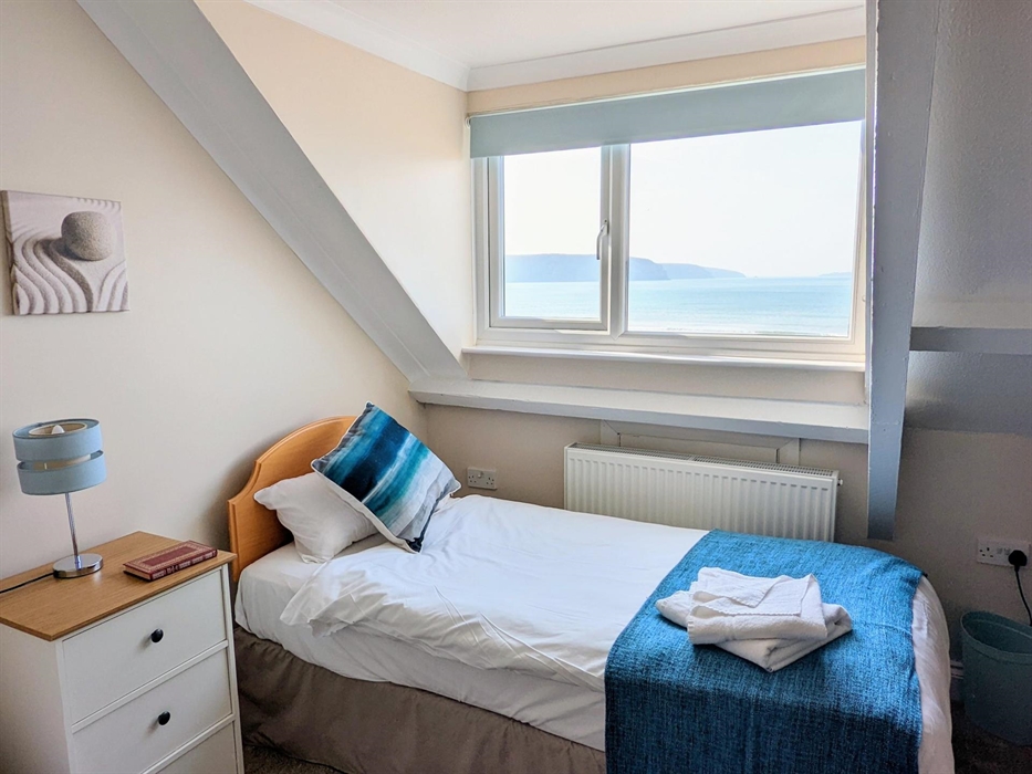 A photograph of one of the beds in the twin room showing the view from the window and the bed made up with towels provided and the beach themed decor.