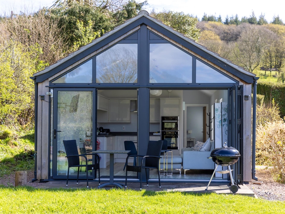The terrace at the front of the Skirrid, showing off the large picture windows, barbecue, and table and chairs
