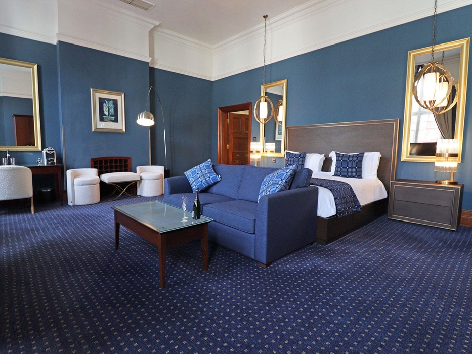 The Henry Belle Suite boasts a stylish Kingside bed, large sofa with coffee table, a desk and comfy chair, and two further comfy chairs