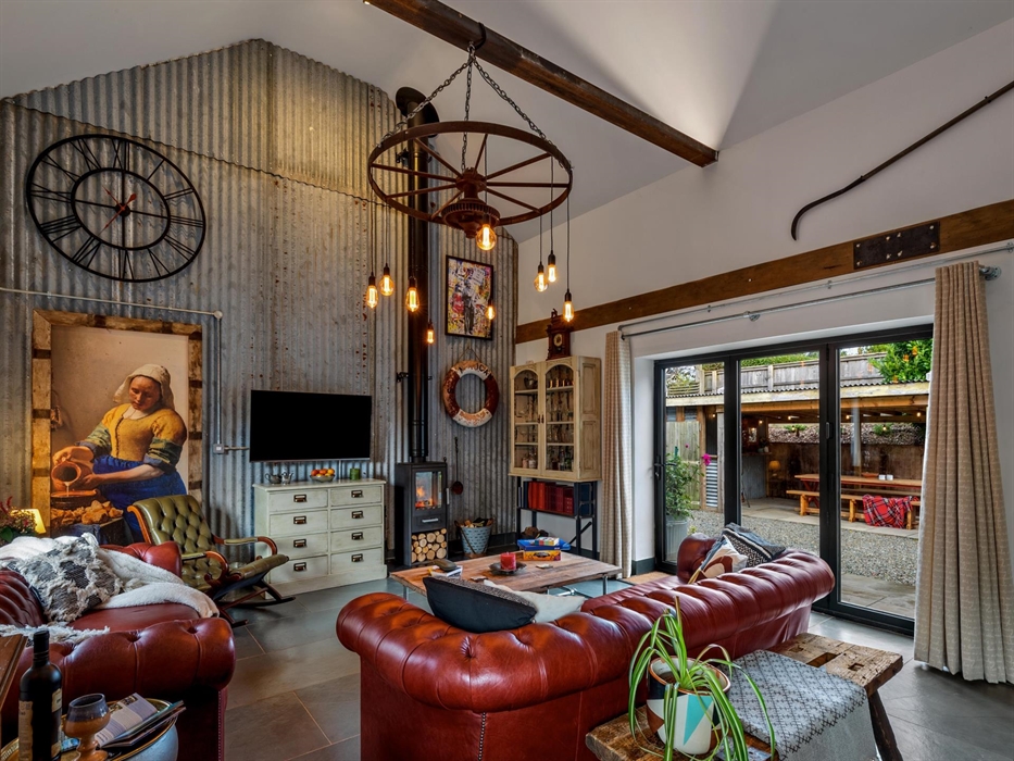 Lounge with Chesterfield sofas, wood burning stove, smart TV, bi-fold door to covered outside patio, BBQ area. Corrogated iron (Zinc) feature wall, ru