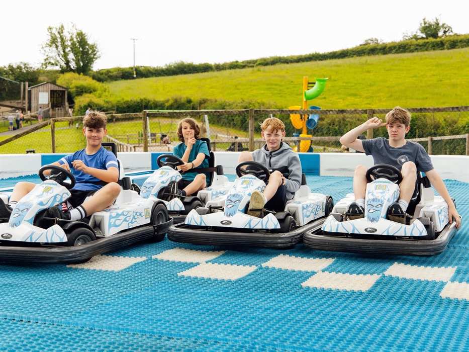 Four boys on the Skiddy cars smiling and ready to start their race!