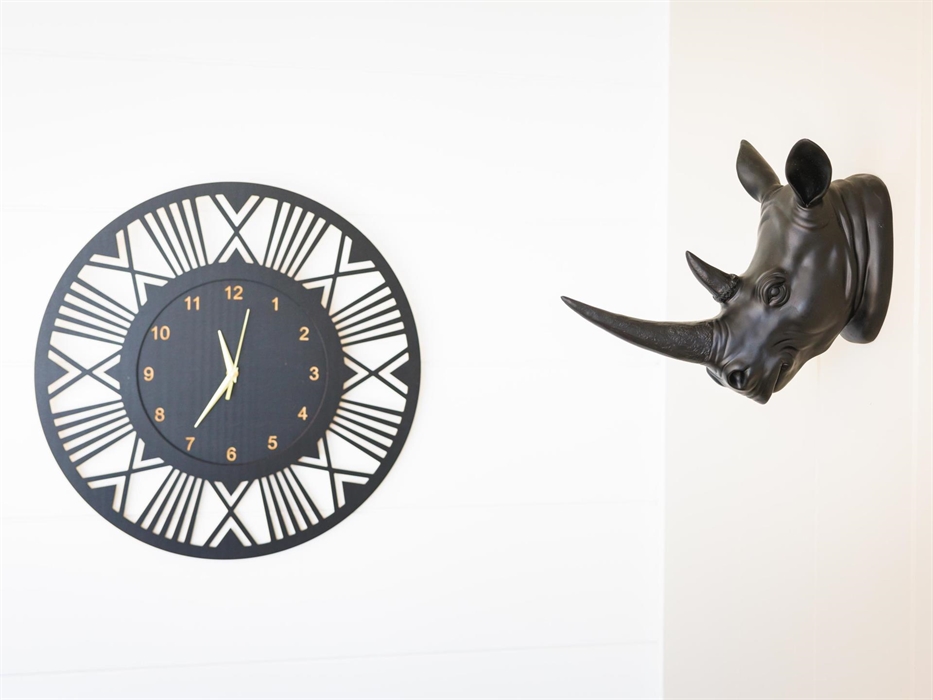 African styled black and gold clock and wall-mounted black rhino head.