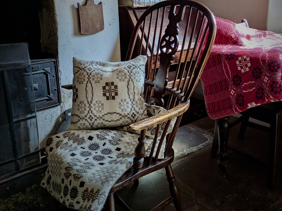 A rocking chair adorned with a blanket and cushion.