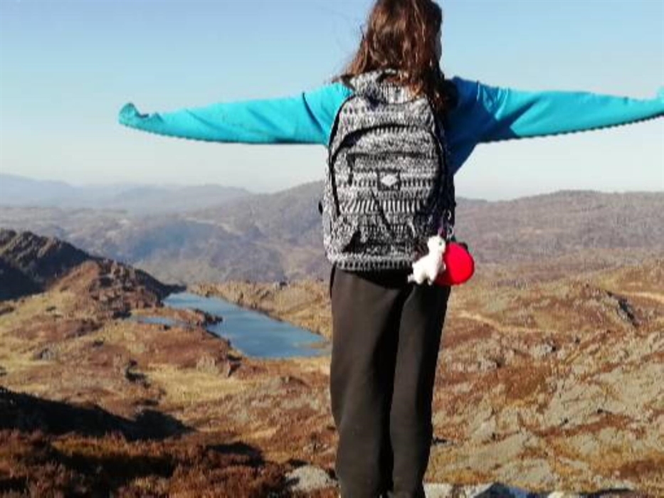 girl with stretched out arms overlooking lake in mountains