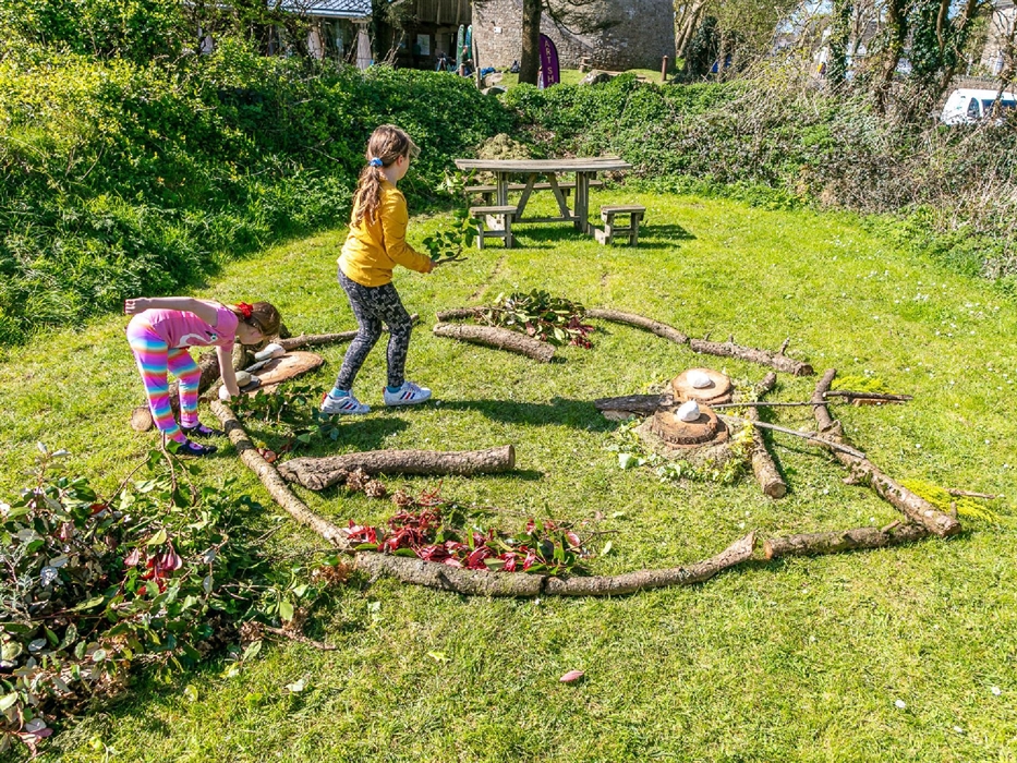 Two children doing outside crafts with leaves and branches