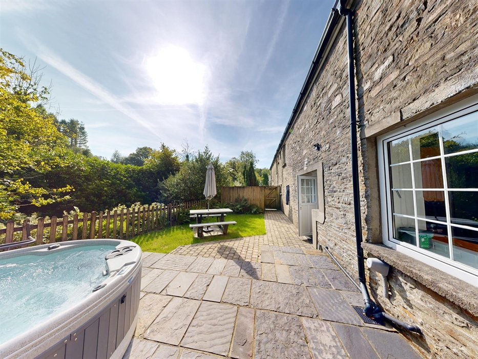Stone terrace and enclosed garden with hot tub, picnic bench, and river views.