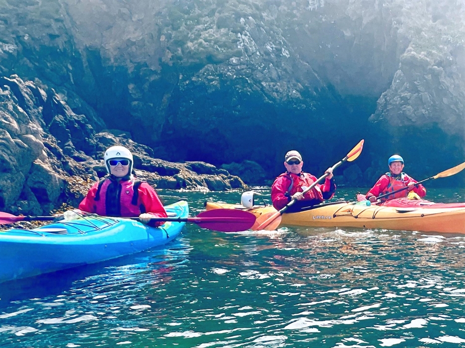 Group of happy sea kayakers in front of cliffs