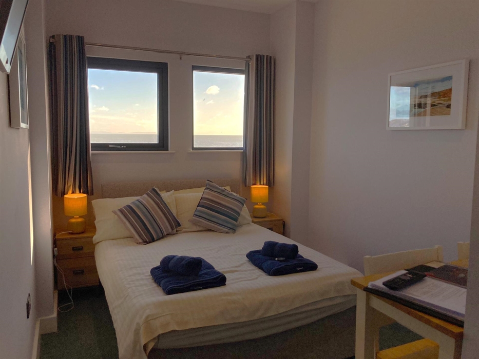 Cosy double room with bar table and chairs, television, and two windows with views directly onto the beach and water.