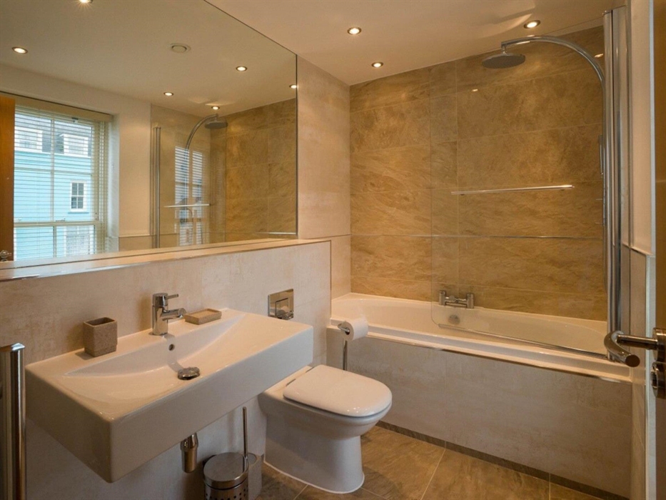 En-suite bathroom showing shower over bath, toilet and sink with mirror