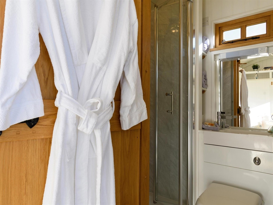 The bathroom itself is compact but it boasts a full-size shower, luxurious bathrobes, and handmade bathroom products.