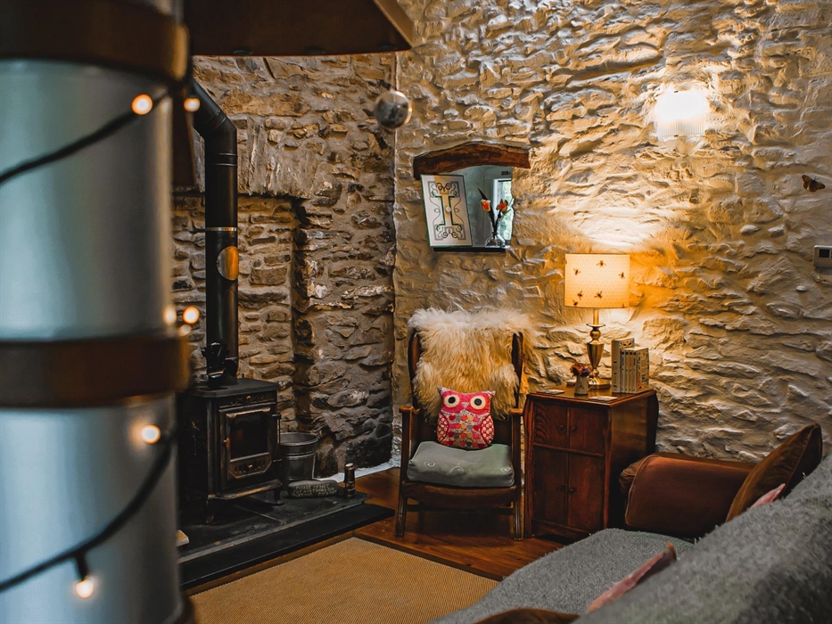 Hen Ffermdy cottage living area with armchair beside the wood burning stove