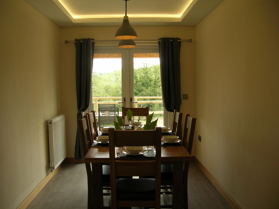 The dining table leads out through patio doors onto decking with a further seating area and Hot Tub.
