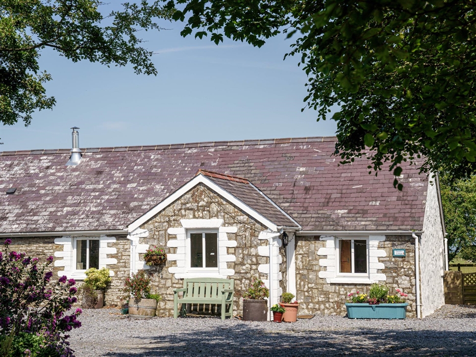 This very attractive stone and slate Welsh cottage with front porch greets holidaymakers as they drive in the gate.  Flower tubs add colour and welcom