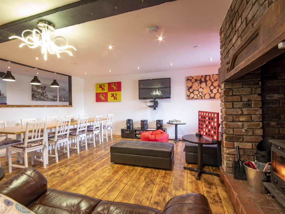 Welsh Row House sitting on a sofa by the log fire in front of the TV on the Wall.  Other seating around and large dining table that seats up to ten gu