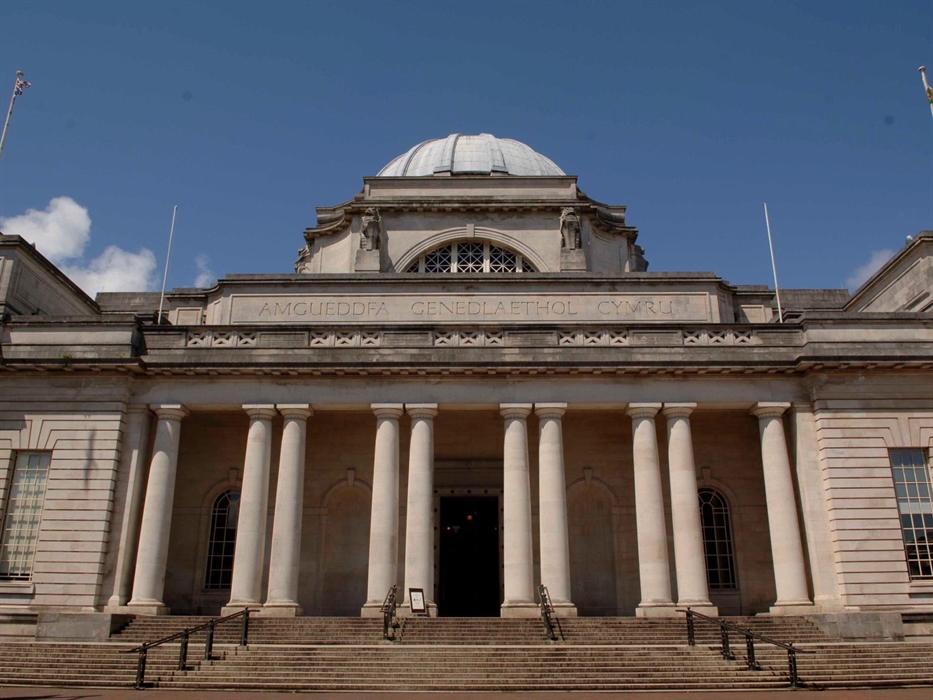 view of the outside of museum building. It looks grand, has steps leading up to the front and there are big stone pillars decorating the frontage.