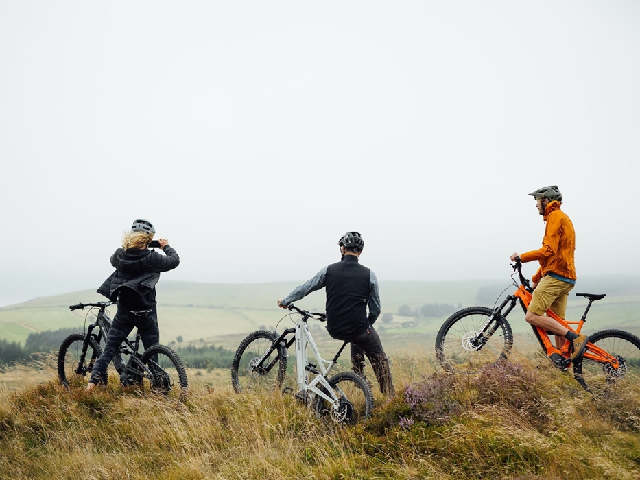 Three cyclists look out across Rosebush on a cloudy day.
