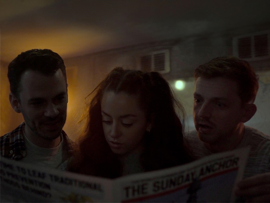 3 players are reading a newspaper in an escape room setting.