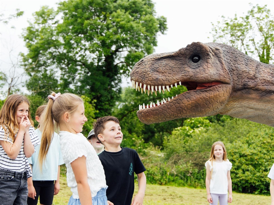 A group of children laughing at Red the T-Rex.