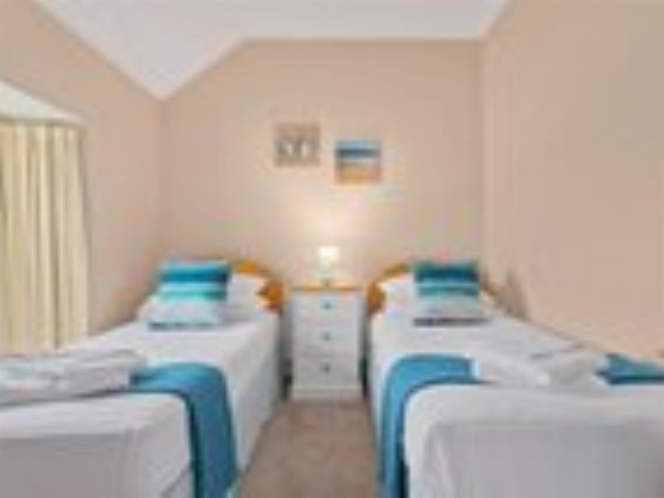 A photograph of the twin bedroom of apartment 2 showing the beds with towels folded and seaside themed pictures on the wall