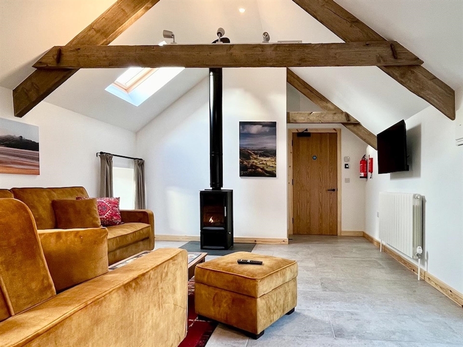 The large open plan lounge area has vaulted ceilings and a modern wood burning stove
