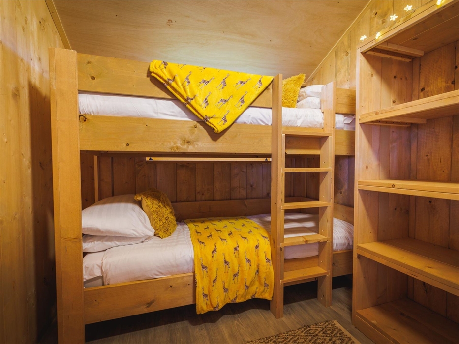 Bunk beds with giraffe patterned blankets and bookcase with fairy lights.