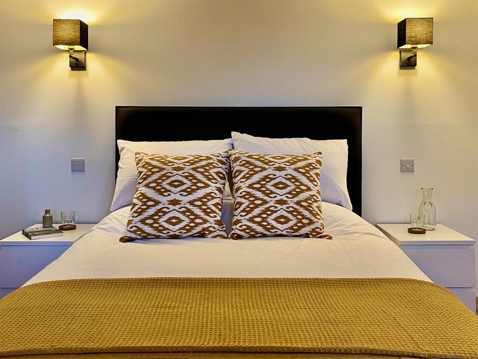 King size bed with crisp white linen and decorative cushions and throw