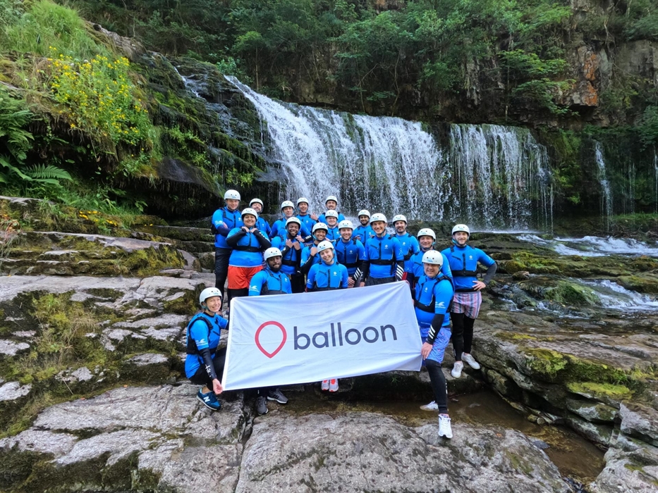 Balloon team holding logo banner during company offsite adventure activity canyoning in Wales
