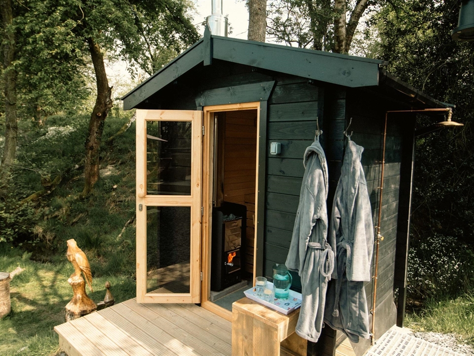 Private wood fired sauna area with robes and an outdoor cold water shower.