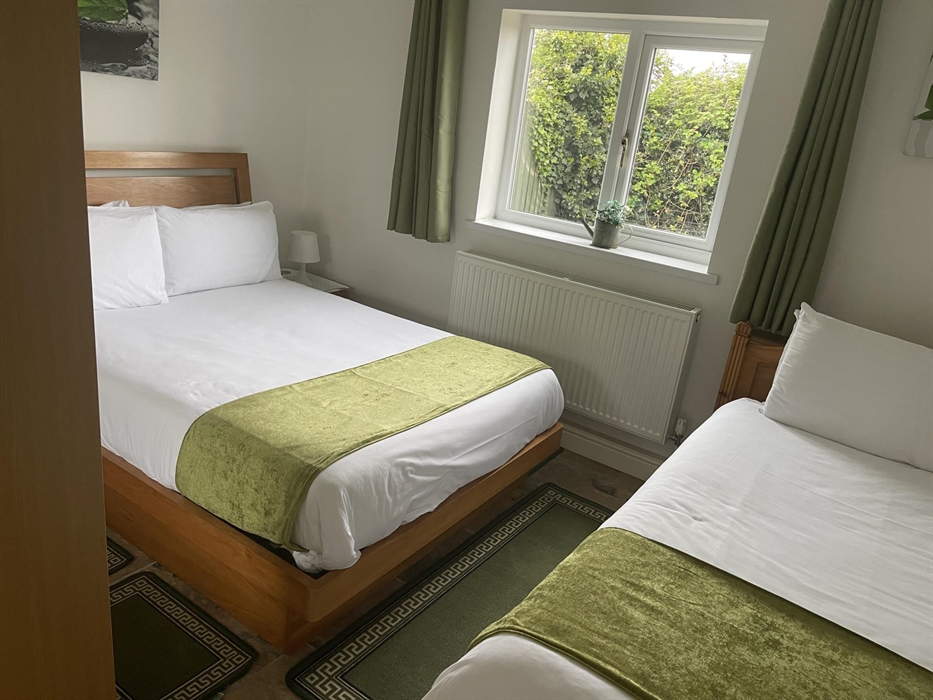 Twin room showing double and single beds, window showing the view  of the private garden area.