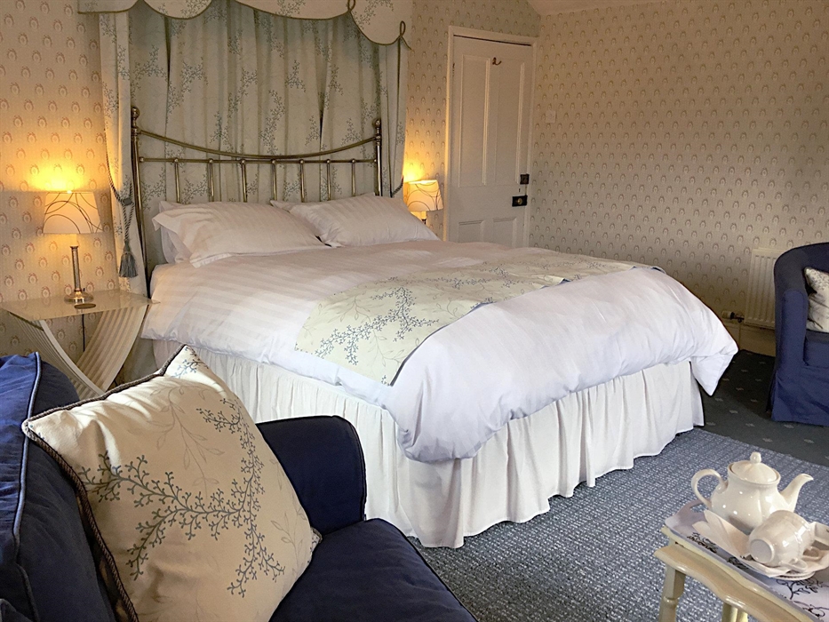 Double room looking towards a king size bed with bedside tables and lamps on both sides, a sofa and coffee table in the foreground.