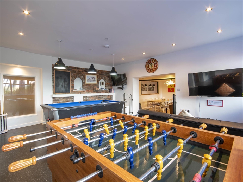 Welsh Row House games room. Seats in front of Xbox with Xbox games Pass.  Football Table and Pool Table leading down some steps to the living area.
