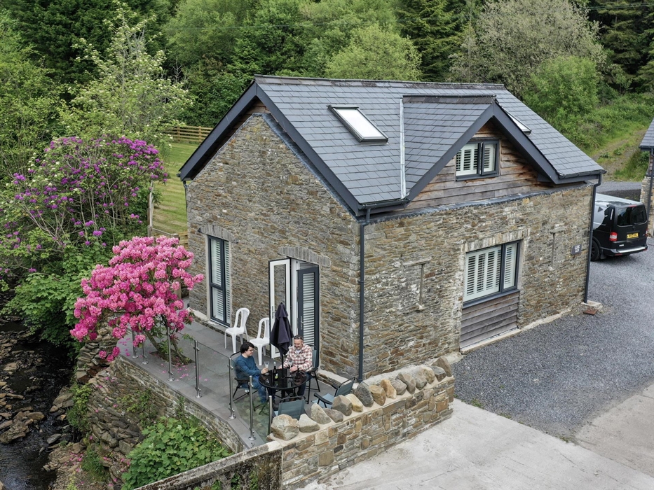 Traditional stone holiday cottage with riverside patio and rhododendron blooming