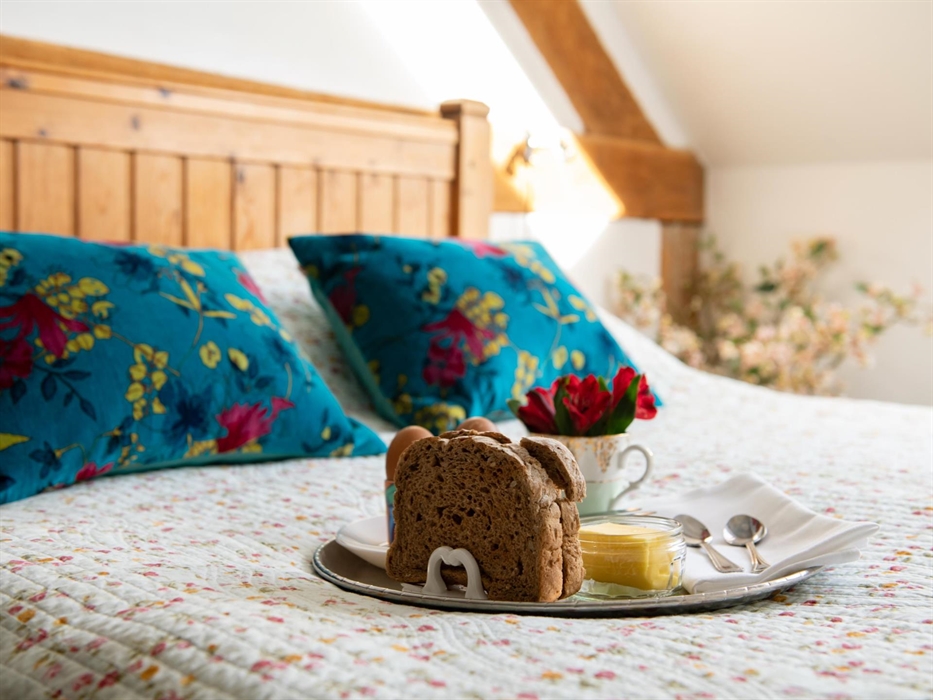 Double bed with breakfast on a tray and flowers.