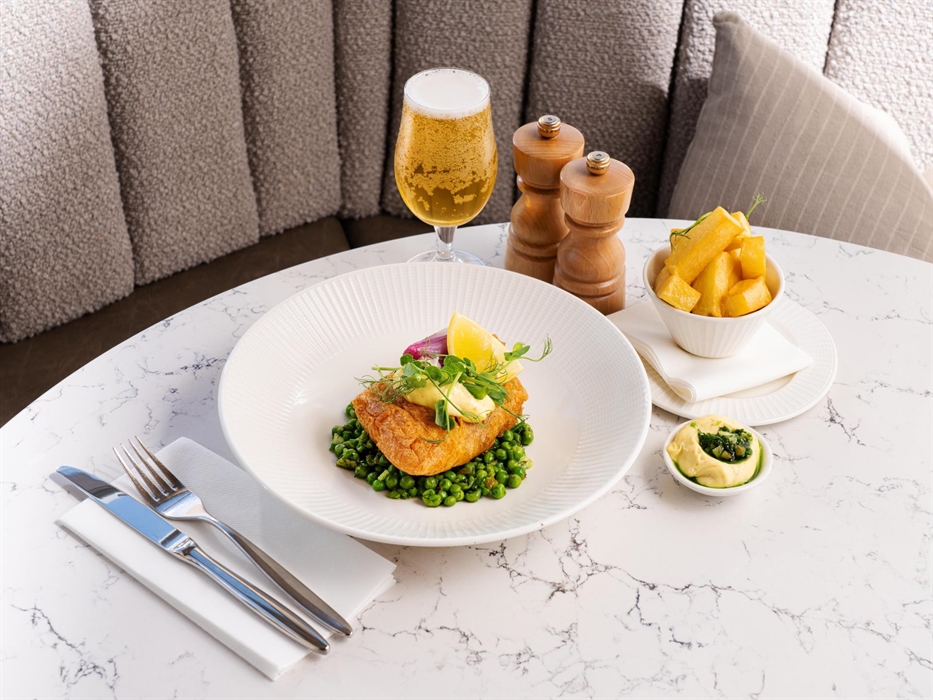 Image of fish and chips on a table, served with beer, at The Goat Restaurant