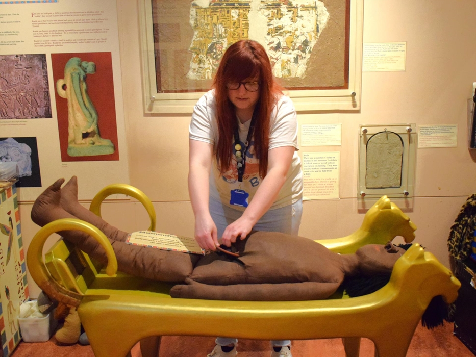 Egypt Centre Volunteer performing Mummification upon the museum's dummy mummified person.