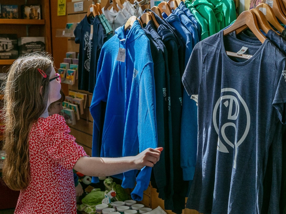 Young girl looking through display of branded clothing in shop