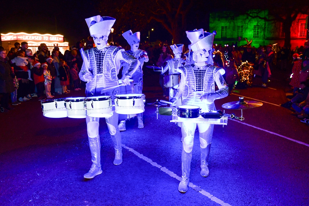Illuminated drummers in festive costume taking part in the Swansea Christmas Parade