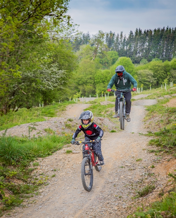 A young rider and her dad riding one of the blue graded trails