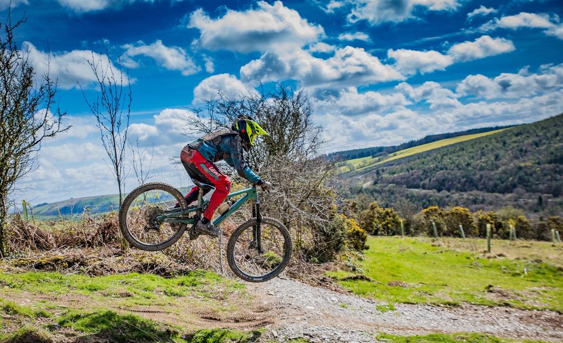 A younger rider jumping on one of the trails.