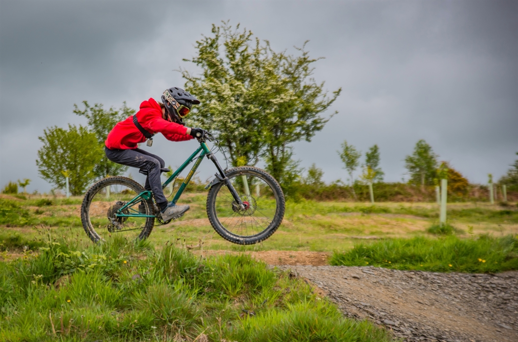 Action shot of a young rider wearing a bright red top against a stormy sky.