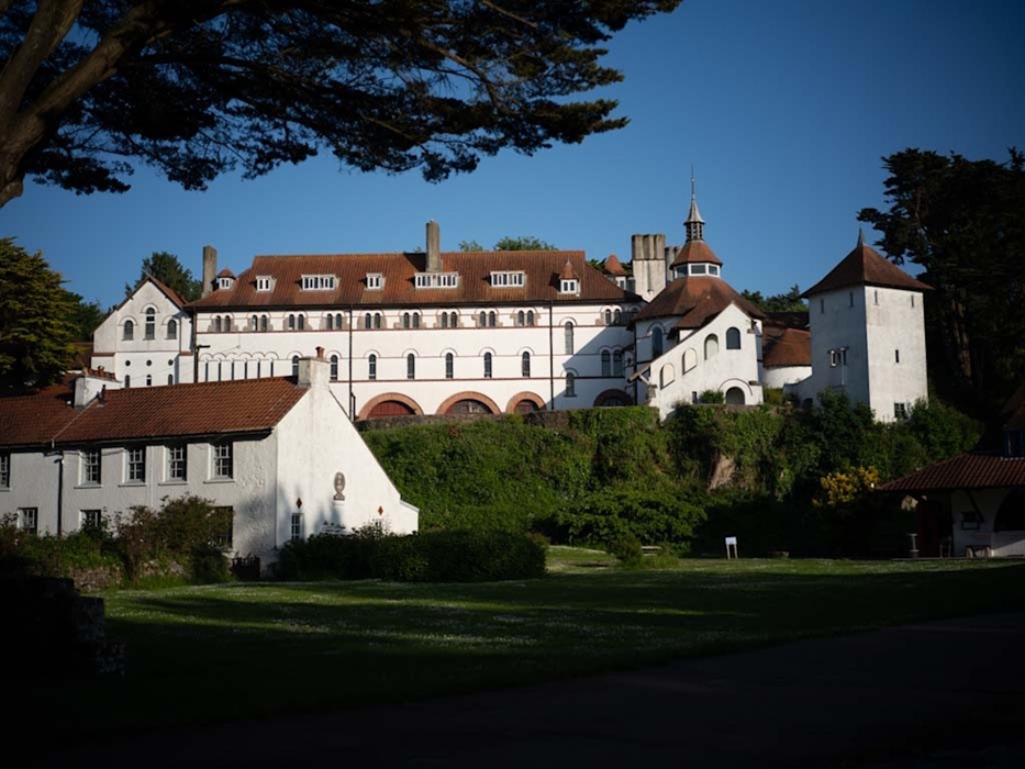 Caldey Abbey and monastery buildings on Caldey Island, surrounded by trees and overlooking the village green.