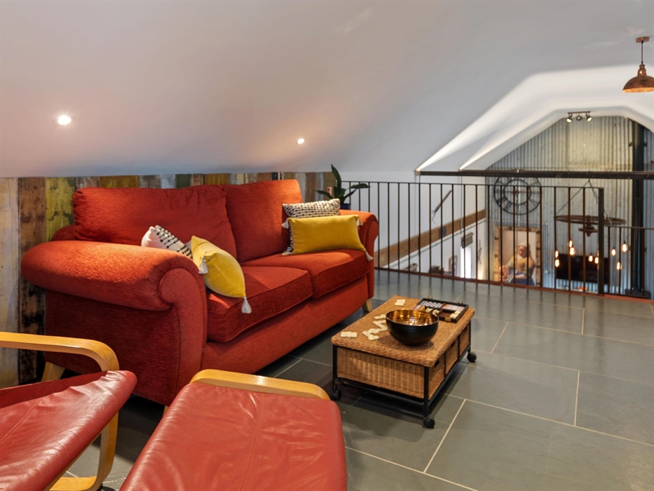 at the top of the stairs landing with large sofa and IKEA chair, smart TV, underfloor heating, clothes hanging rail, doors leading to bedroom and fami