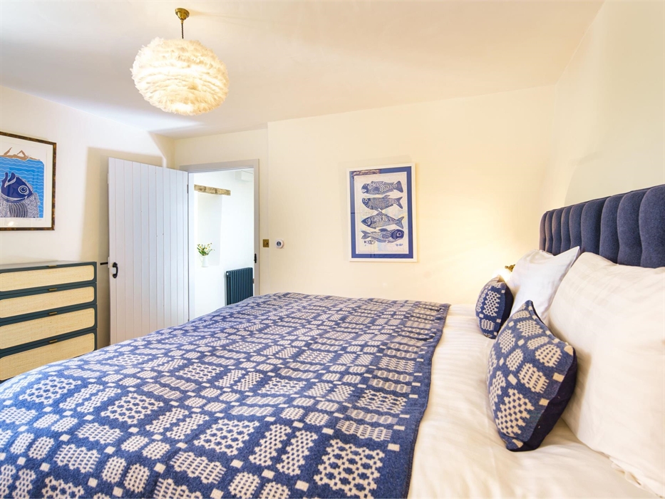 Yr Ffald cottage sleeps 4 and this bedroom has a new super king bed which can be split into two singles. It has a blue and white welsh blanket and cus
