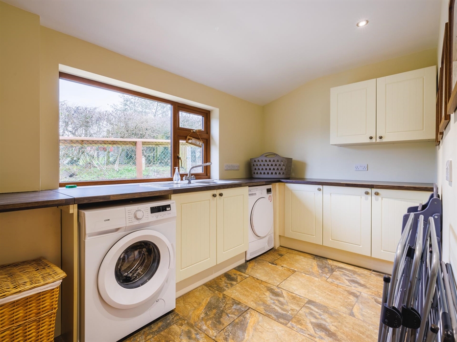 Laundry room with washing machine, tumble dryer, clothes drying racks, washing basket and laundry bin.