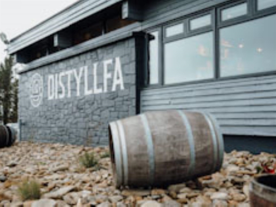 Distillery exterior with barrel in foreground and logo on the wall in the background
