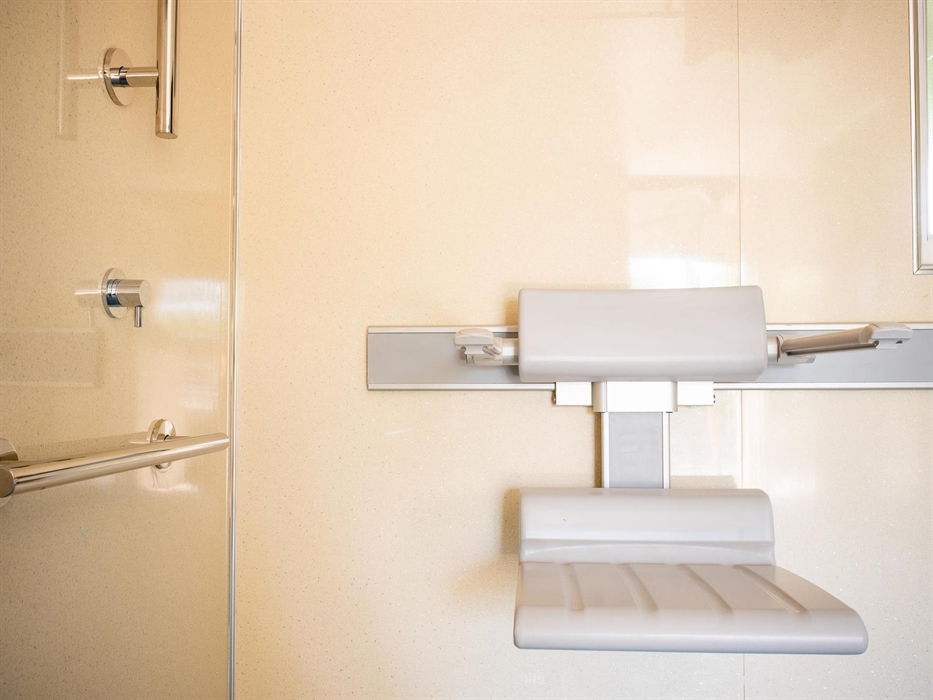 A grey shower chair shown in close up in an accessible shower