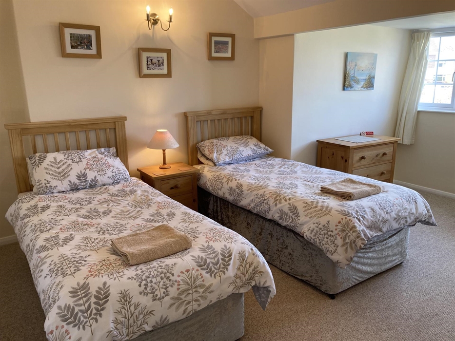 Spacious second bedroom with twin single beds and views of rear garden and the sea beyond